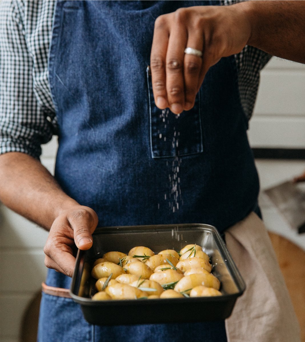 A chef sprinkling salt over some potatoes at Saint Bibiana